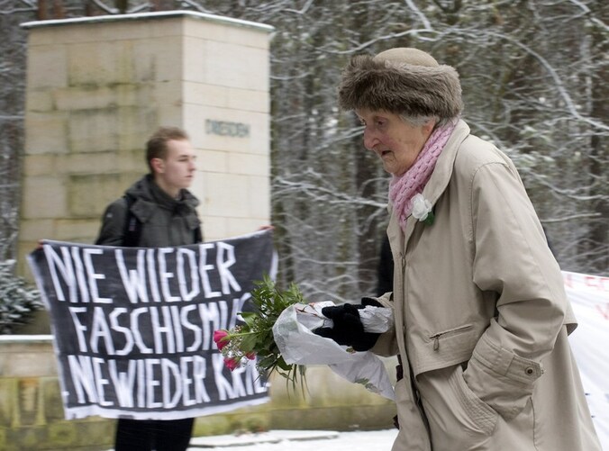 Mensen leggen bloemen neer op het kerkhof.