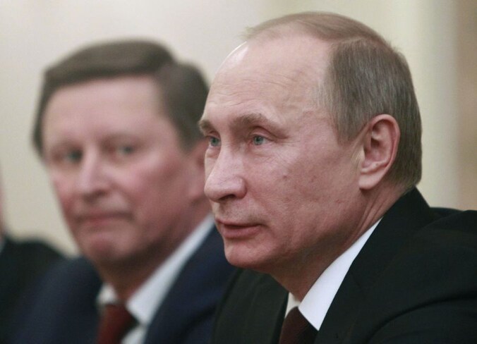 President Poetin met op de achtergrond zijn stafchef, Sergei Ivanov.