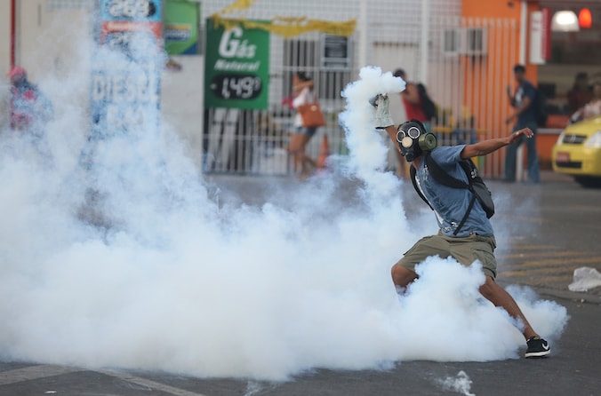 Een betoger aan het centraal station in Rio gooit een traangasgranaat terug naar de politie.