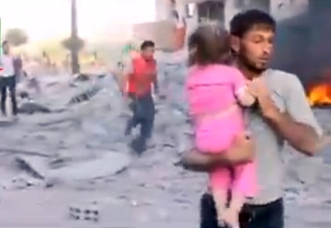 Een Syriër draagt een gewond meisje weg na een aanval in Raqqa.