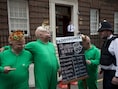 Medewerkers van een gokkantoor poseren met babymaskers voor een bord waarop potentiële namen voor de baby van Kate en William staan.