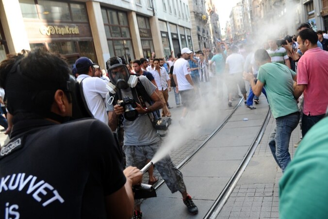 Een agent gebruikt traangas tegen betogers in Istanbul.
