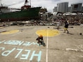 Een Filipijnse vrouw schildert een oproep voor help op straat in het zwaargehavende Tacloban.