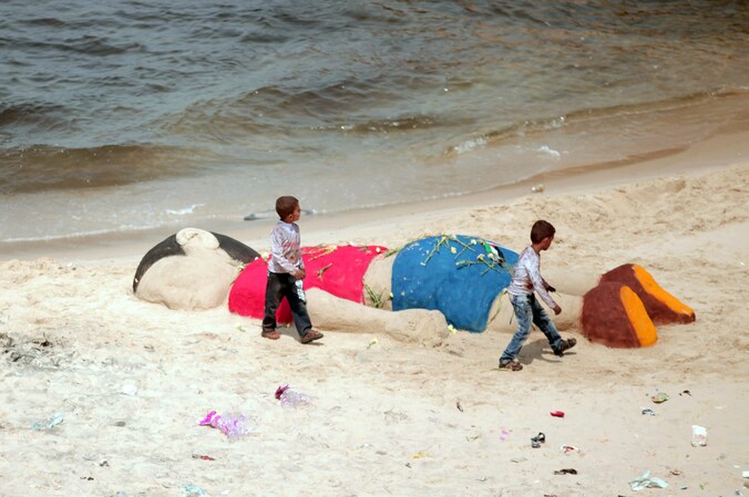 Palestijnse jongetjes bij de zandsculptuur van Aylan in Gaza.