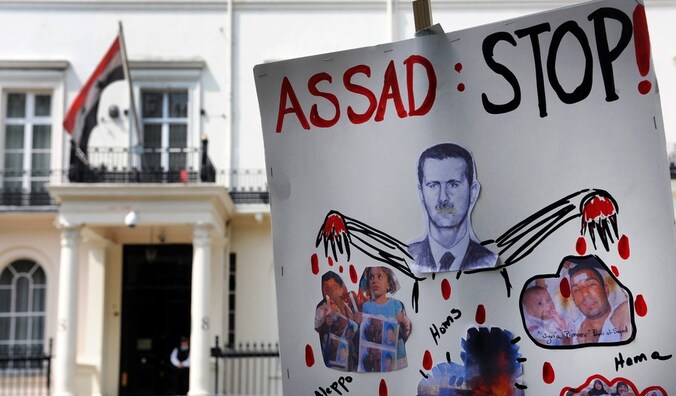 Protestanten tonen een anti-Assad-bord aan de Syrische ambassade in Londen.