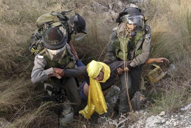 Israëlische soldaten overmeesteren een Palestijnse stenengooier.