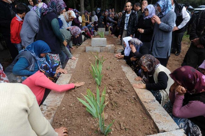 Nabestaanden rouwen bij de graven van slachtoffers.