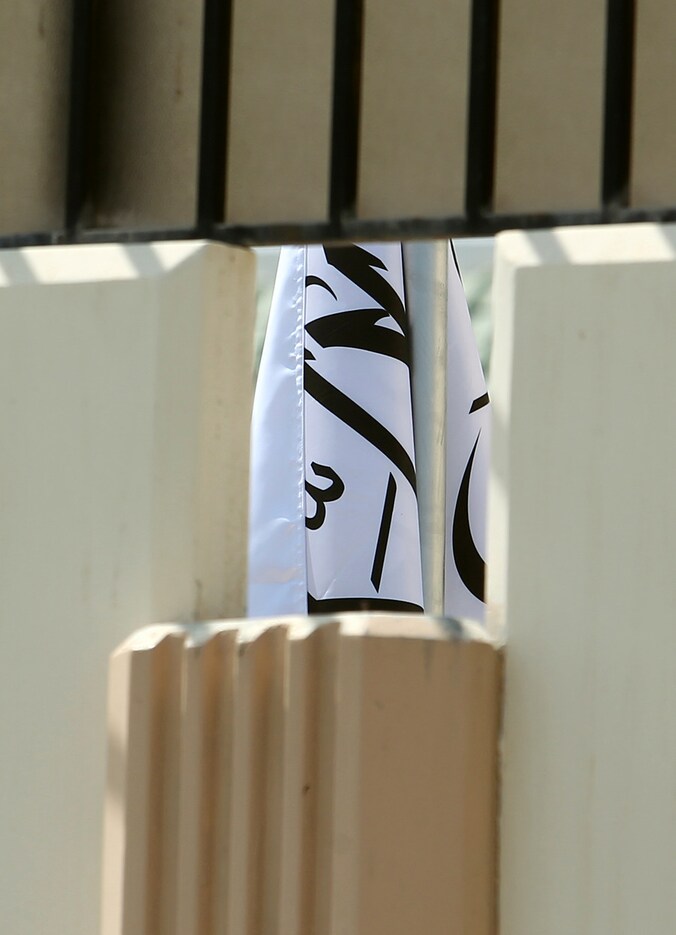 Door een muur is een stukje zichtbaar van de gewraakte vlag in het kantoor van de Taliban in Doha, Qatar.