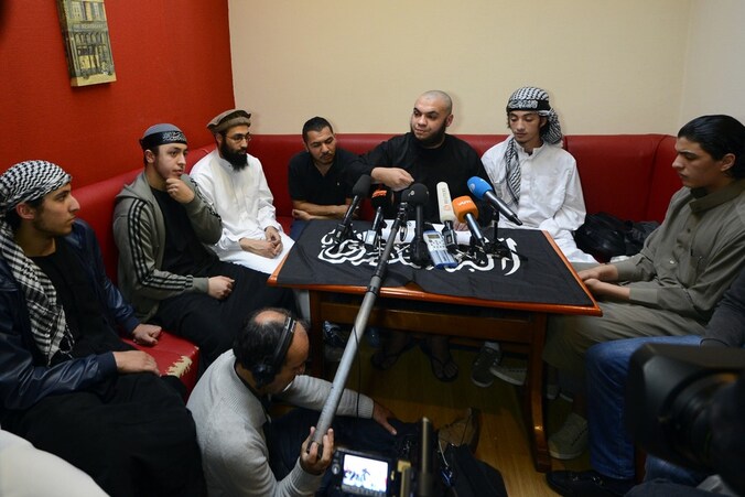 Abu Mujahid (midden) van Sharia4Belgium tijdens de geïmproviseerde persconferentie van vanavond.