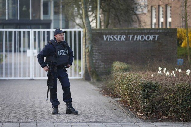 Een zwaarbewapende agent voor de gesloten poort van het Visser 't Hooft lyceum in Leiden.