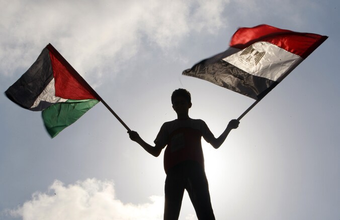 Een Palestijn zwaait met een Egyptische en een Palestijnse vlag in Gaza-stad.