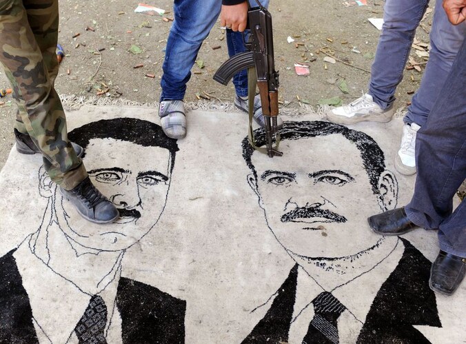 Een afbeelding van president Assad en zijn vader Hafez, de vorige president van Syrië, worden vertrapt.