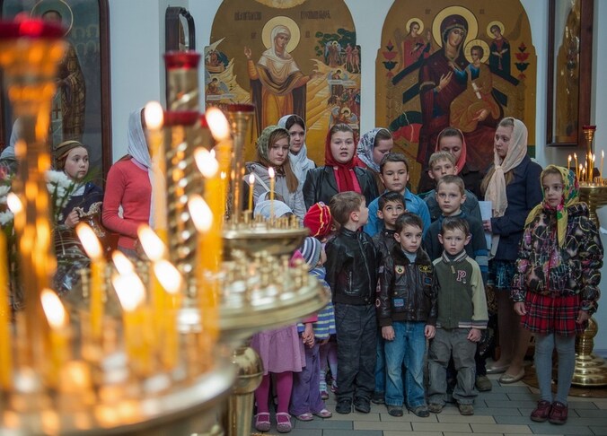 Oekraïense kinderen wachten op de mis in een orthodoxe kerk in de stad Slavjansk. Ook het Orthodoxe Pasen wordt dit weekeinde gevierd.