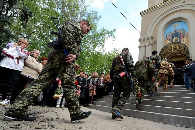 Gewapende mannen in camouflagepakken, vandaag bij een herdenkingsdienst voor eerder omgekomen mannen in Slavjansk.