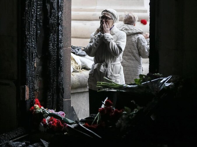 Een vrouw staat voor de ingang van het afgebrande vakbondsgebouw in Odessa. Meer dan veertig mensen kwamen om het leven.