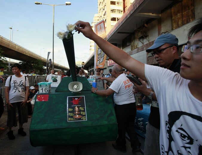 Demonstranten in Hong Kong steken bloemen in een nagebouwde tank tijdens de herdenking van het bloedbad op het Tiananmenplein