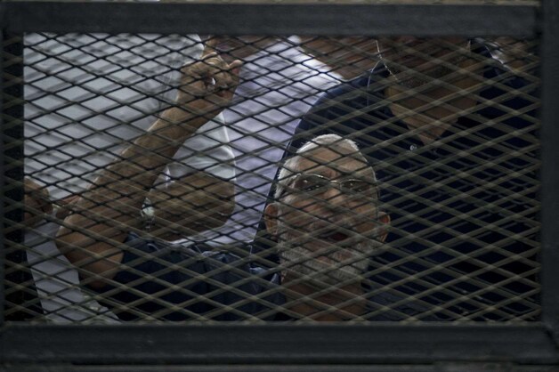 De gevangen leider van de Moslimbroederschap Mohamed Badie gebaart vanuit zijn kooi naar andere leden van de verboden beweging.