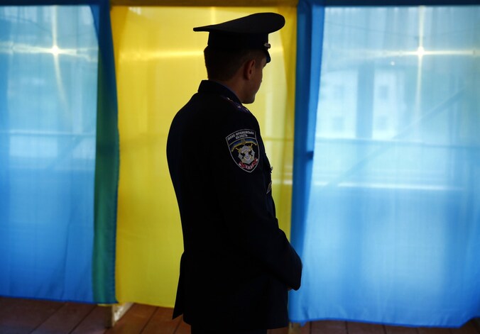 Een Oekraïnse politieagent voor enkele stemhokjes in het de provincie Ivano-Frankivsk Oblast.