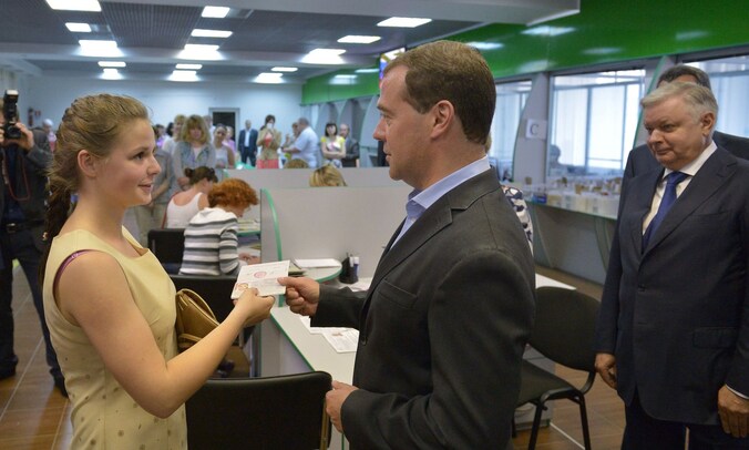 Dmitri Medvedev deelt een Russisch paspoort uit aan een jonge vrouw op de Krim.