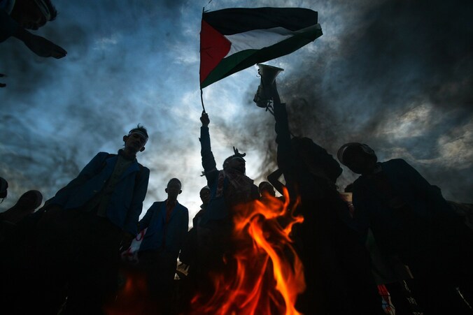 Indonesische betogers houden de Palestijnse vlag in de lucht terwijl ze een Israëlische en Amerikaanse vlag verbranden.
