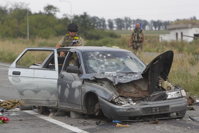 Een Oekraïense soldaat onderzoekt een vernietigde auto bij een checkpoint in de buurt van Donetsk.