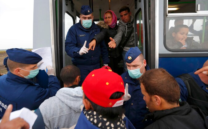 Agenten begeleiden vluchtelingen op een bus in de Roszke, aan de grens met Servië. Tegen begin volgende maand wil Hongarije klaar zijn met de bouw van een hek van prikkeldraad aan de grens.