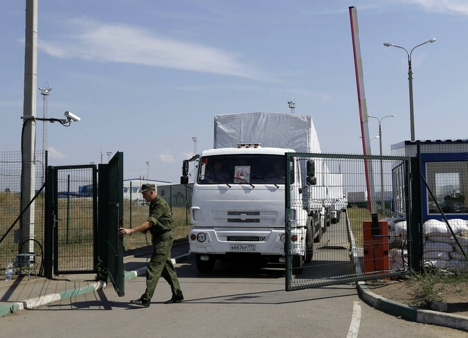 Een Russische bewaker opent de grenspoorten voor de eerste trucks richting Oekraïne.