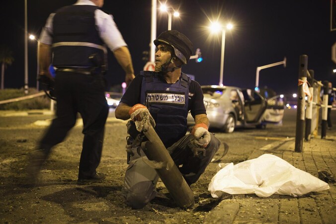 Een Israëlische expert in explosieven van de politie verwijdert de restanten van een raket uit Gaza.