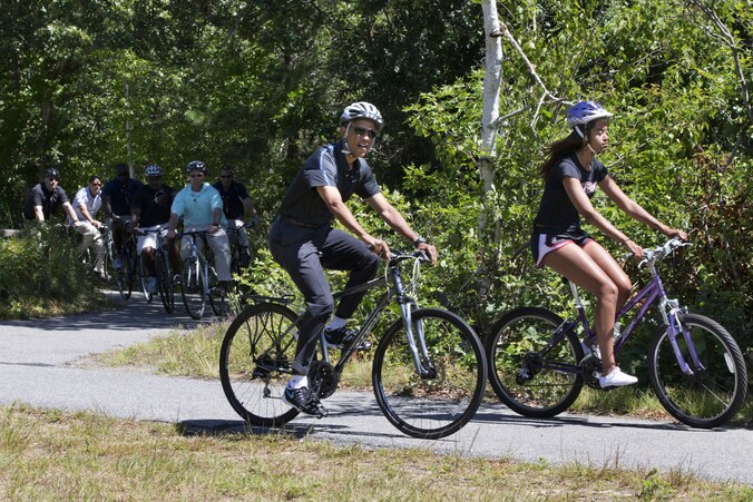 Barack Obama maakt tijdens zijn vakantie een fietstochtje met zijn dochter Malia, waarbij hij gevold wordt door beveiligers