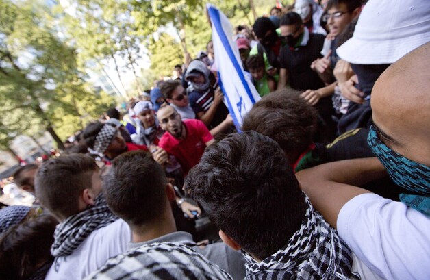 De Israëlische vlag wordt door deels gemaskerde demonstranten in brand gestoken.