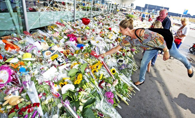 Een vrouw legt op Schiphol bloemen neer ter nagedachtenis van de slachtoffers van de neergehaalde MH17.