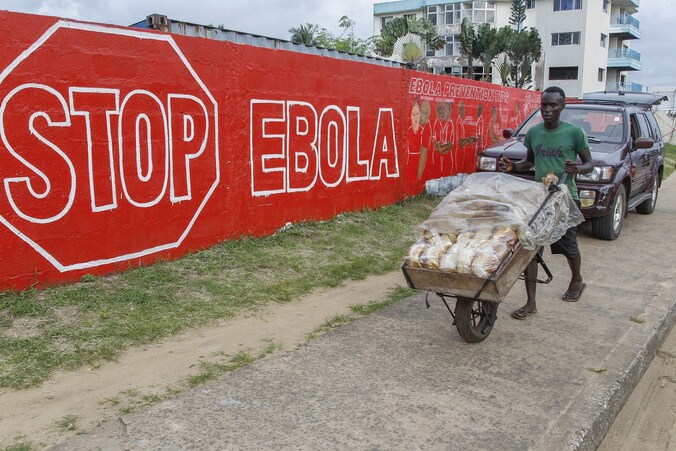 Een man uit Liberia duwt zijn broodkar langsheen een sensibiliseringscampagne ter bestrijding van het dodelijke Ebola-virus.