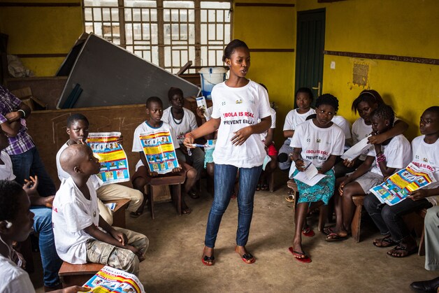 Een voorlichtster vertelt kinderen in Sierra Leone hoe ze kunnen voorkomen met ebola te worden besmet.