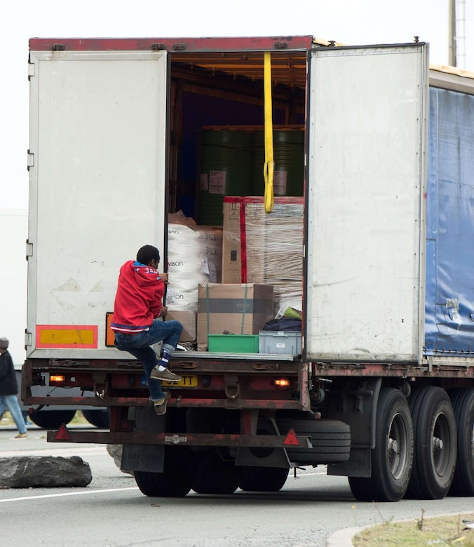 Een illegale migrant springt op een vrachtwagen in de haven van Calais.