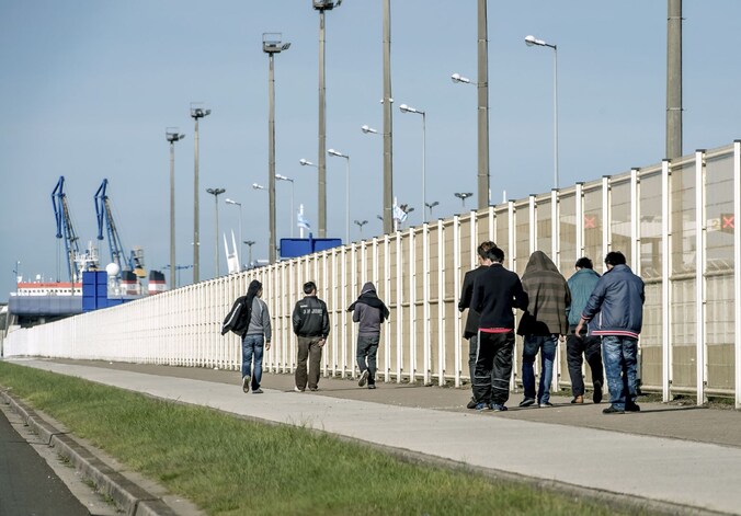 Migranten wandelen in de haven van Calais.