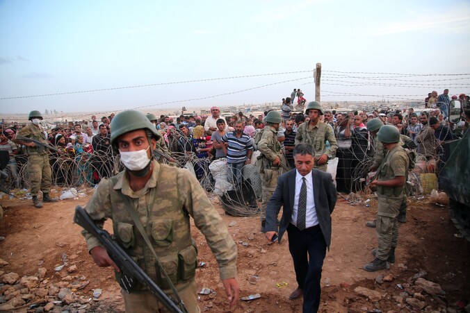Turkse soldaten bewaken Syrische vluchtelingen die net de grens zijn overgestoken op de vlucht voor het geweld van IS.