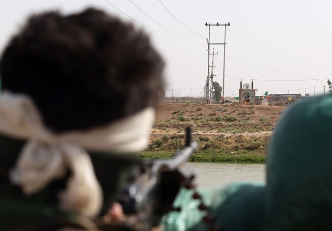 Een Iraakse strijder kijkt naar het niemandsland tussen waar Iraakse troepen zijn gelegerd en rebellen van ISIS in Taaza, op 25 kilometer van Kirkoek.