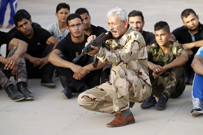 Een aanhanger van het sjiitische Mehdi-leger geeft schietles aan nieuwe rekruten, die zullen worden ingezet in de strijd tegen het soennitische ISIS.