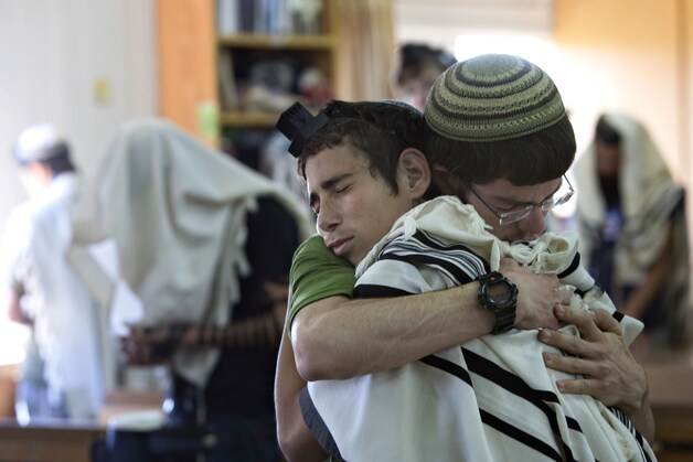Twee Israëlische joodse studenten omhelzen elkaar voor een gebed in de synagoge waar twee van de vermiste Israëlische jongeren studeerden.