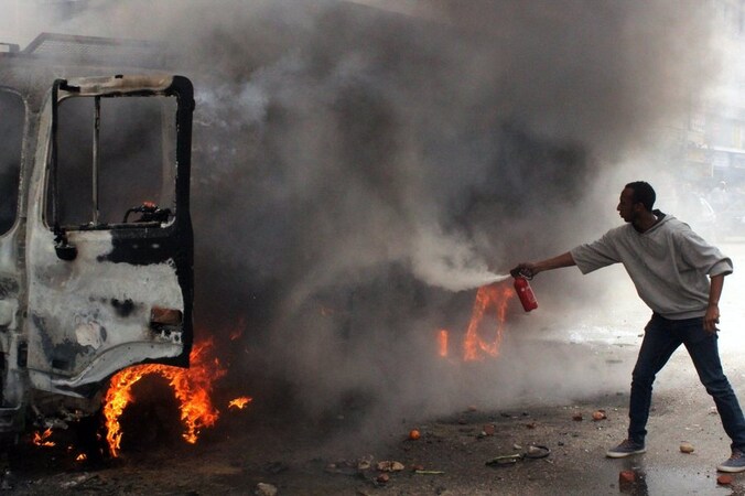 Burgers proberen een politieauto te blussen die tijdens rellen in brand was gestoken.