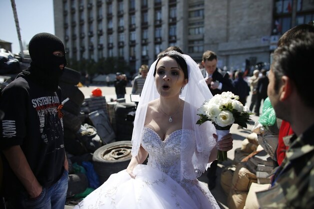 Een bruid passeert pro-Russische separatisten bij een barricade voor het bezette overheidsgebouw in Donetsk.