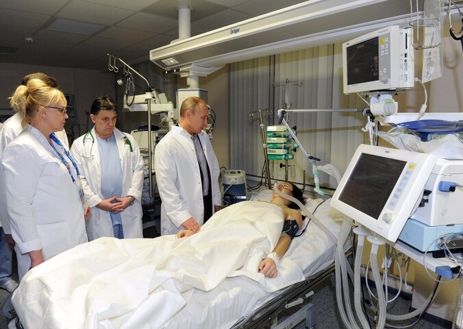 De Russische presindent Vladimir Putin bij het bed van Maria Komissarova.