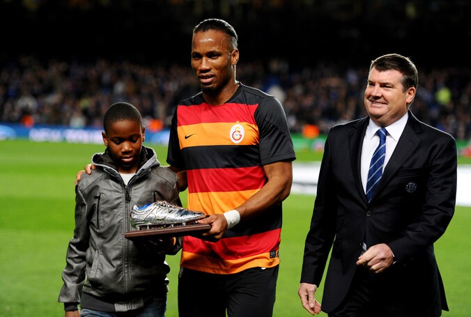 Didier Drogba, samen met zijn oudste zoon Isaac, krijgt een zilveren schoen van Chelsea overhandigd.