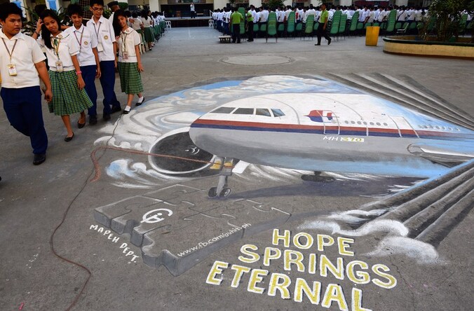 Scholieren wandelen naast een muurtekening van de vermiste Malaysia Airlines-vlucht MH370.