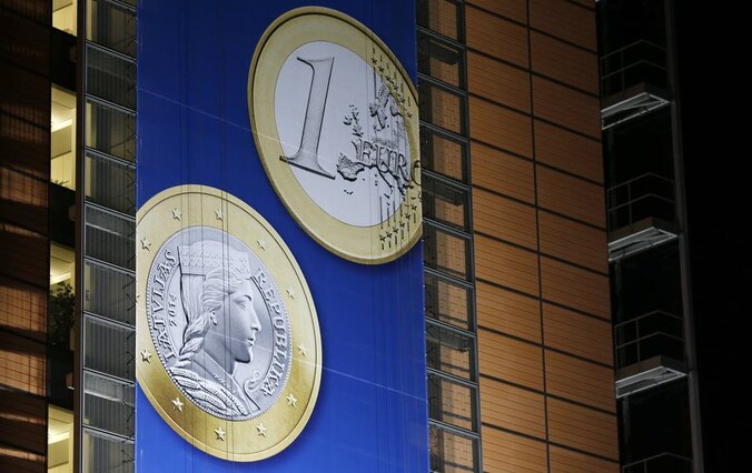Een banner met de nieuwe Letse 1 euromunt die in Brussel aan het gebouw van de Europese Commissie hangt.