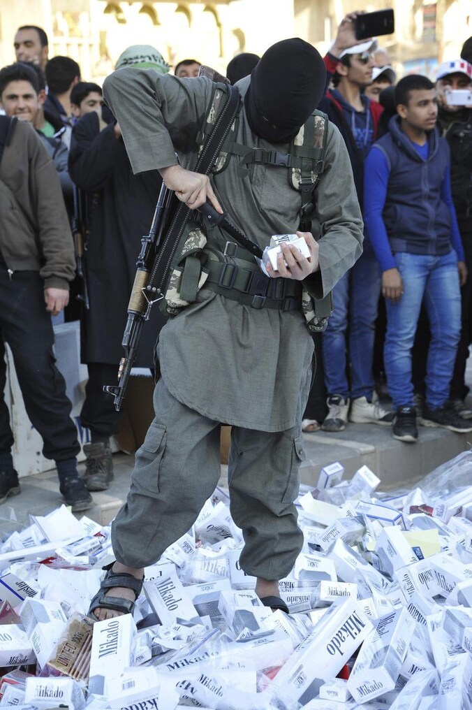 Een strijder van de ISIL (Islamitische Staat in Syrië en de Levant) vernietigt in beslag genomen sigarettenpakken in de stad Raqqa. (archieffoto)