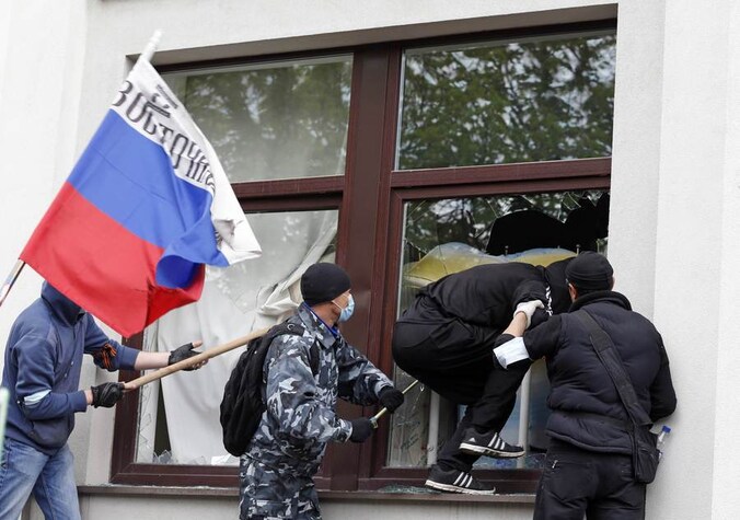 Pro-Russische activisten in Loehansk slaan de ruiten van het lokale overheidsgebouw in Loehansk kapot.