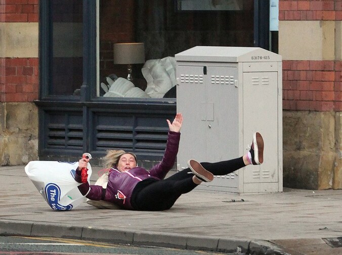 Hevige windvlagen maakten voetballen in Manchester te gevaarlijk, zoals ook deze dame ondervindt.