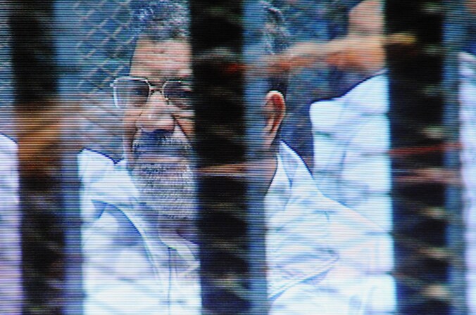 Mohammed Mursi staat in een glazen kooi in de rechtbank in Caïro.