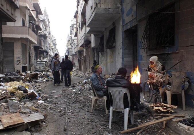 Inwoners van Homs houden zich warm rondom een vuur in een van de belegerde wijken van de stad.